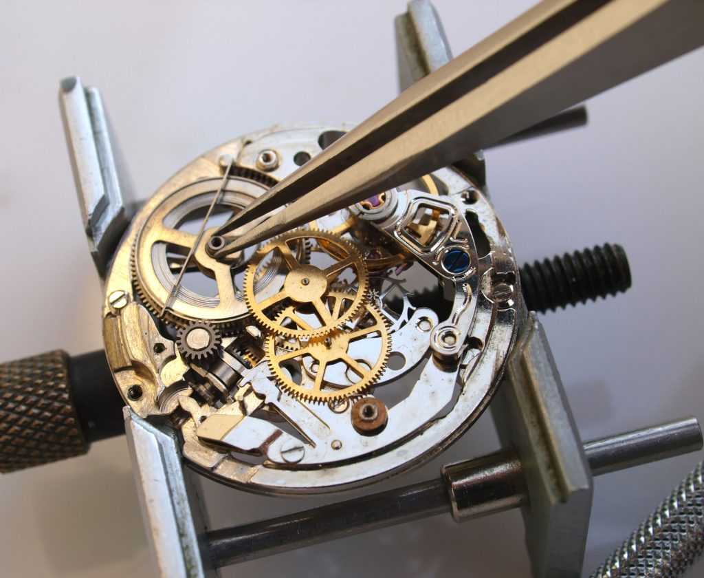 A watchmaker repairing a watch on the workshop bench